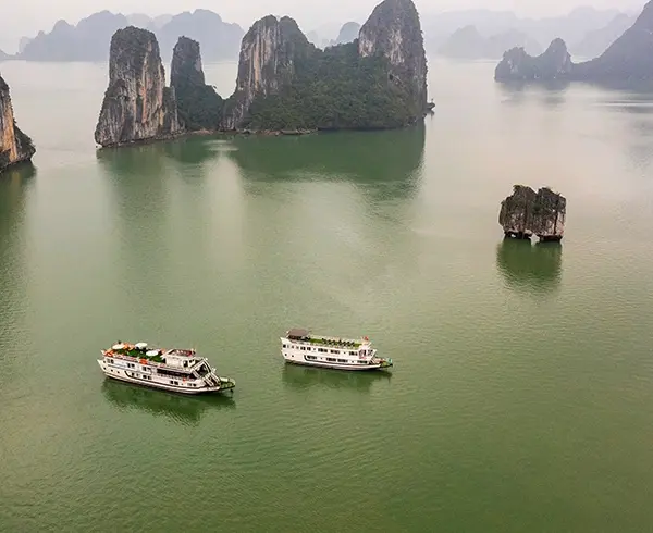Cruise boat sailing through limestone islands in Halong Bay