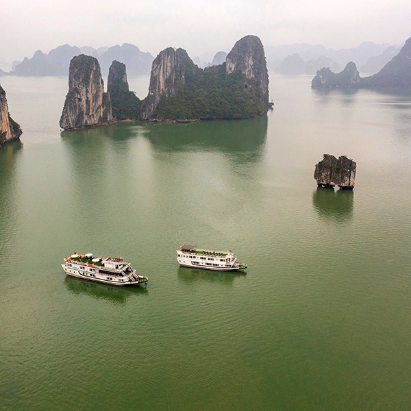 Cruise boat sailing through limestone islands in Halong Bay