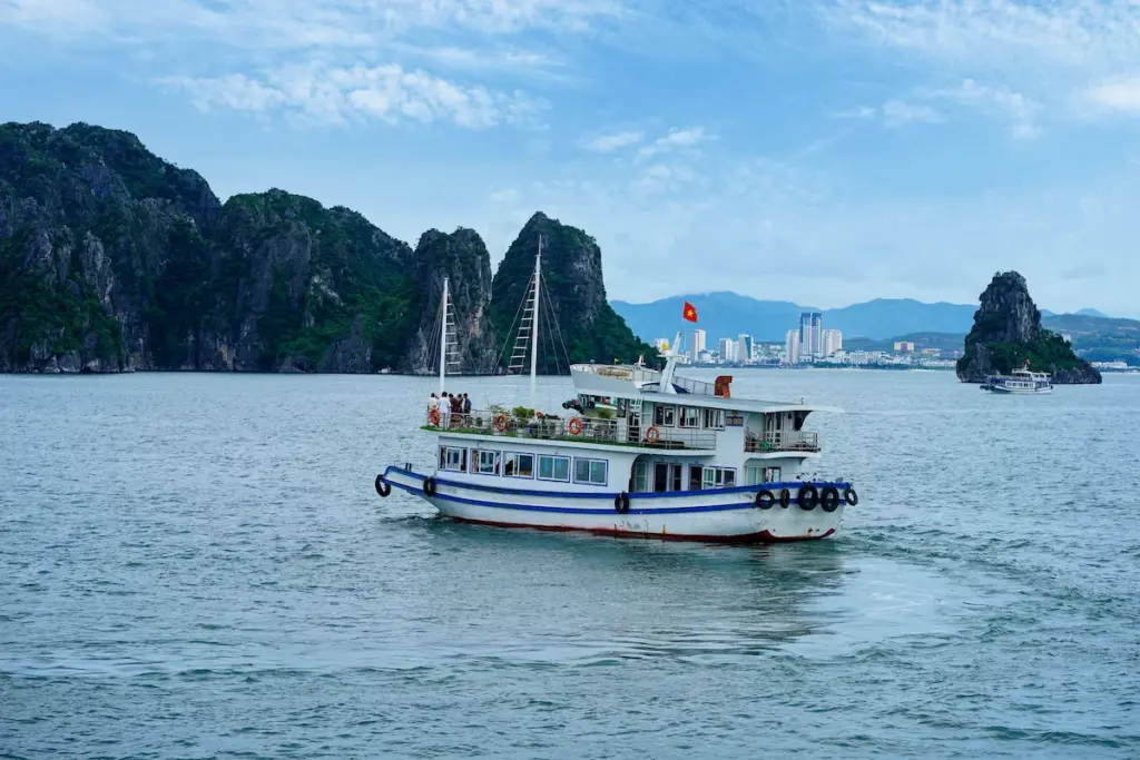 Halong Bay cruise boat sailing past iconic limestone islands in Vietnam