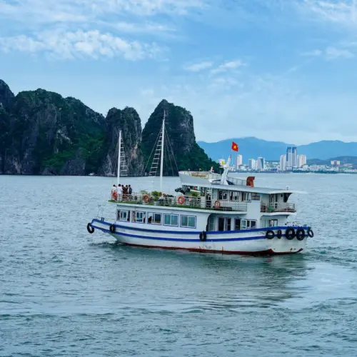 Halong Bay cruise boat sailing past iconic limestone islands in Vietnam