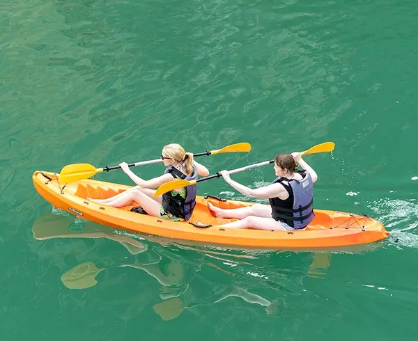 Two travelers kayaking across the emerald waters of Halong Bay