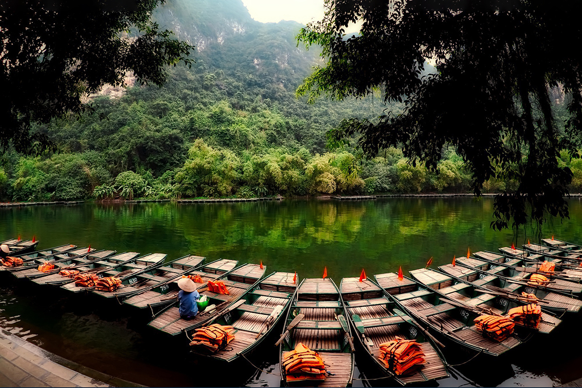 Traditional wooden sampan boats on emerald river at Trang An Ninh Binh