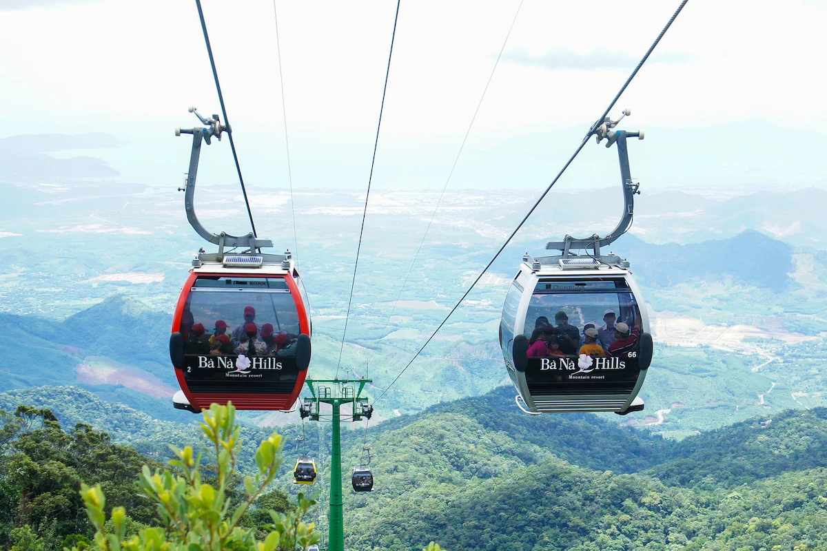 Red and white cable cars above forested mountains at Ba Na Hills