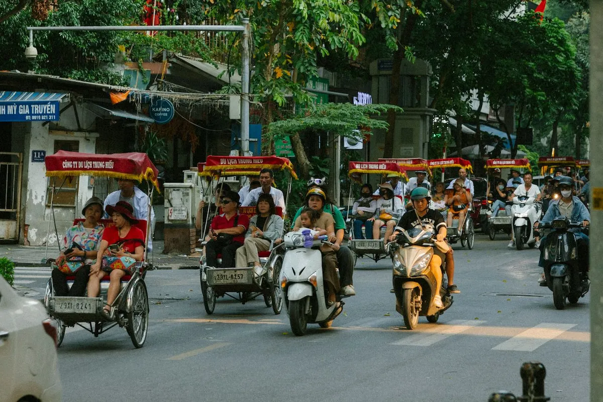Tourists ride cyclo rickshaws through Hanoi streets, illustrating the best time to visit Hanoi
