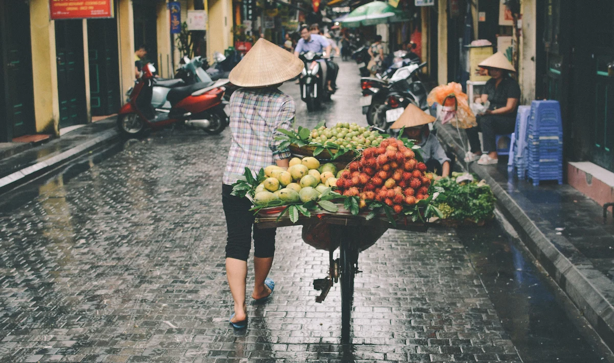 A Vietnamese street vendor carries fresh fruit through Hanoi's Old Quarter