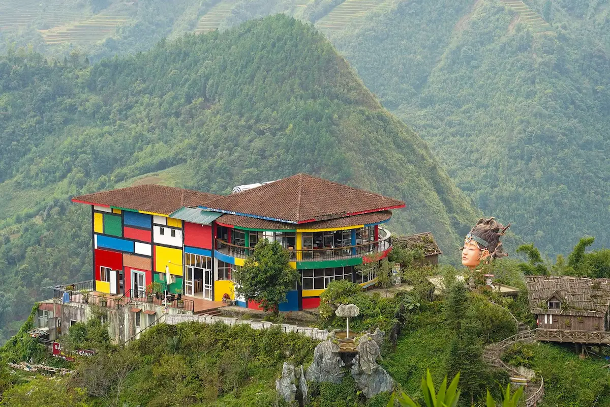 Colorful building and large sculpture above a forested valley