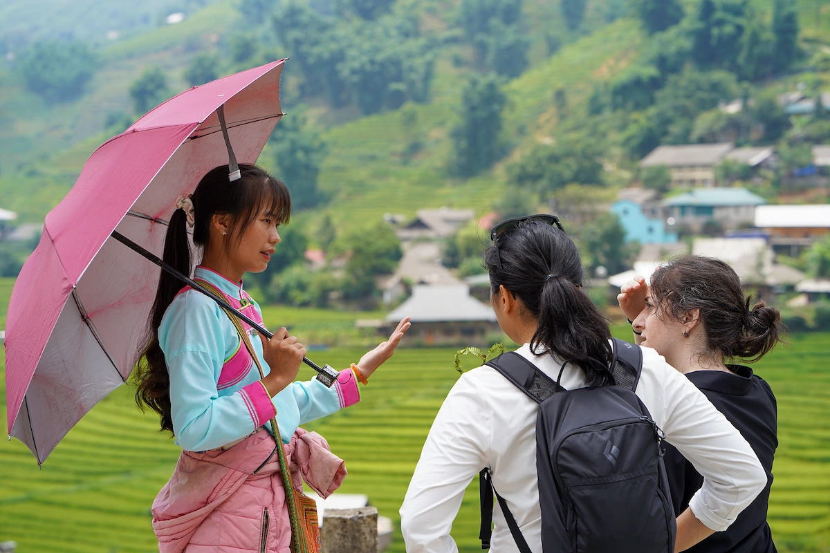 Local guide speaks with two travellers beside Sapa rice fields